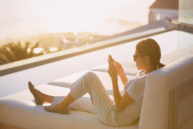 Jeune femme qui utilise son smartphone sur sa terrasse